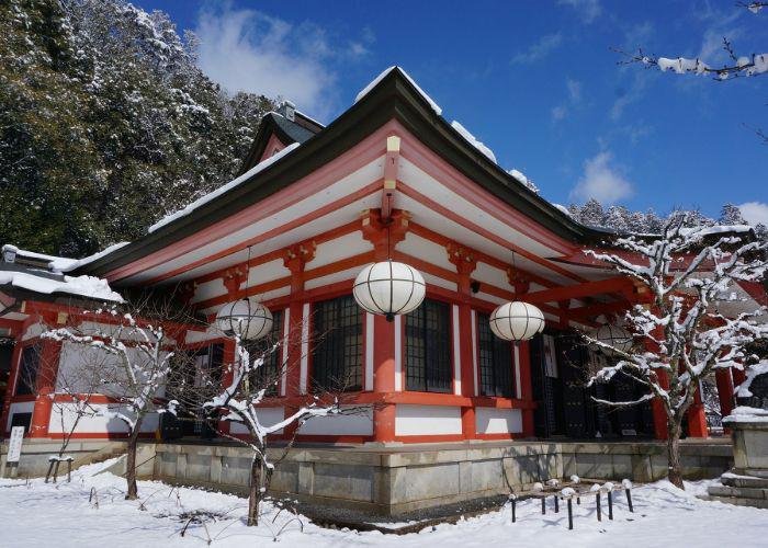 An image of a red and white building at Kuruma-dera Temple covered in snow