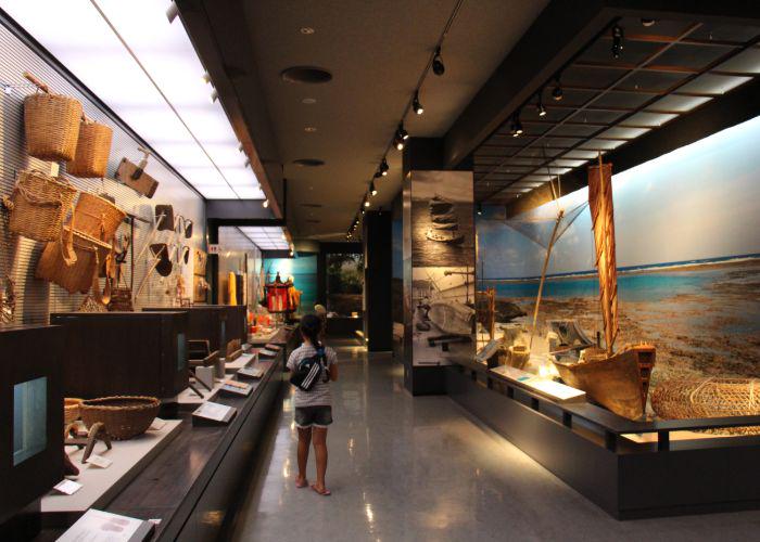 An internal shot of the Okinawa Prefectural Museum, with baskets and a wooden boat