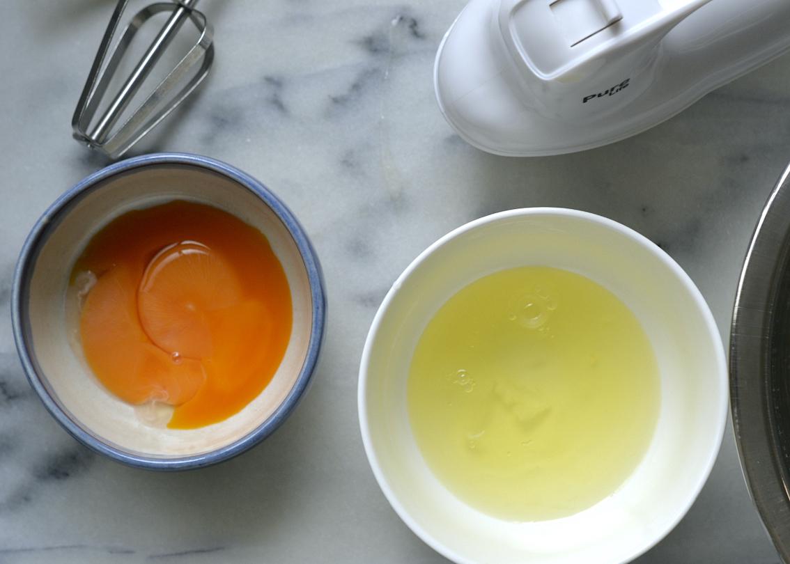 Bowl of egg yolks and bowl of egg whites on a marble countertop