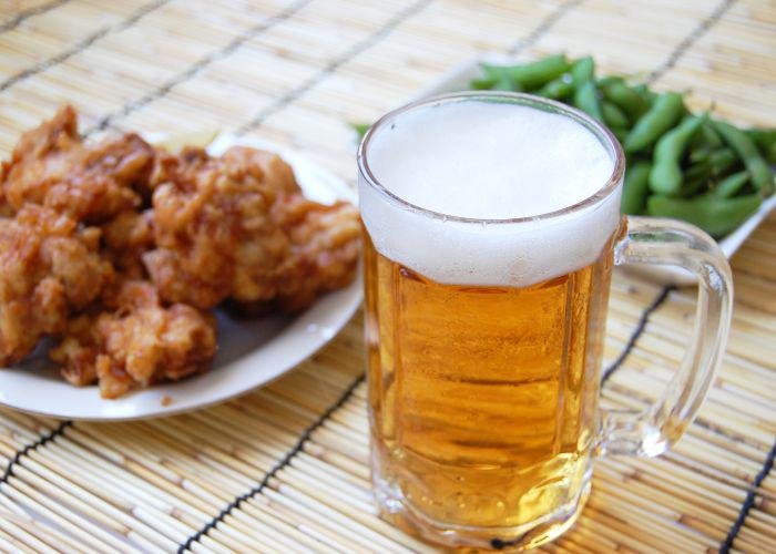 Large glass of Japanese beer with karaage fried chicken and edamame beans