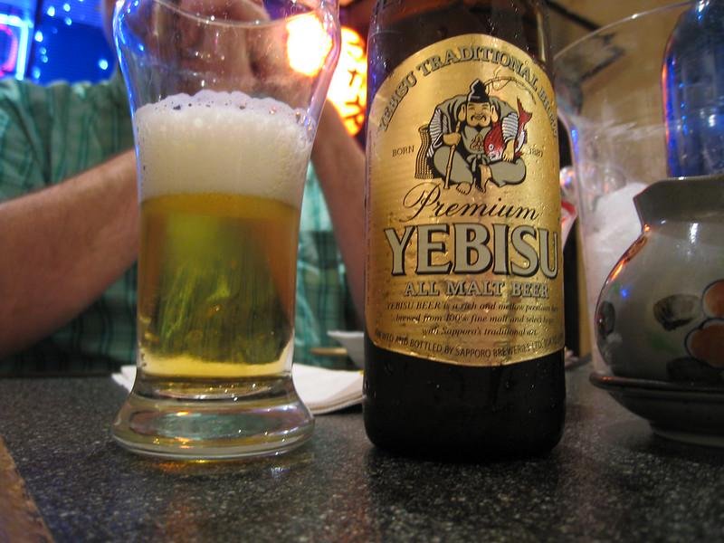 Bottle of Yebisu Premium in a bar with a glass next to it