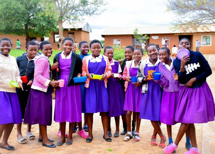 large group of primary school girls posing for a photo with their meal cups in hand