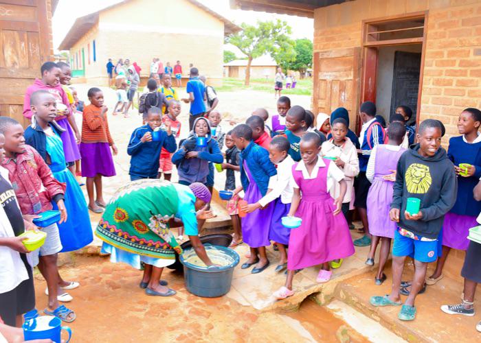 primary school children waiting to recieve their school meals from a staff member