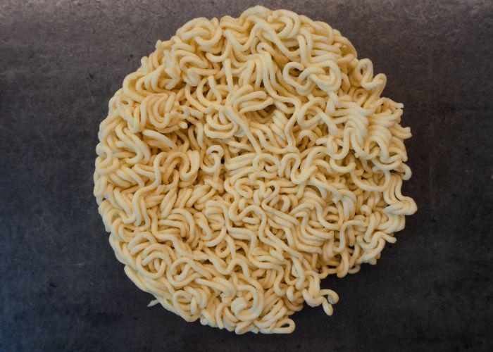 An overhead image of a circle of uncooked curly ramen noodles