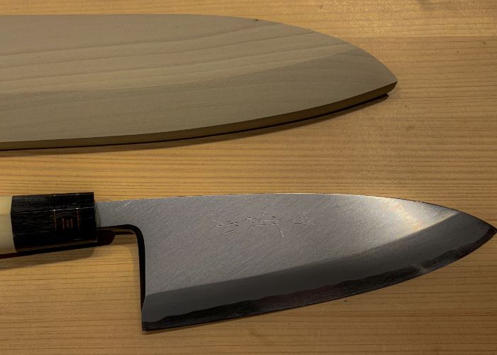 An overhead image of a deba knife and its wooden casing