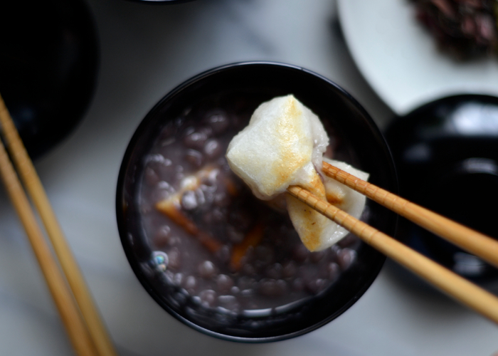 Close-up of hot oshiruko in a bowl, with chopsticks holding up mochi