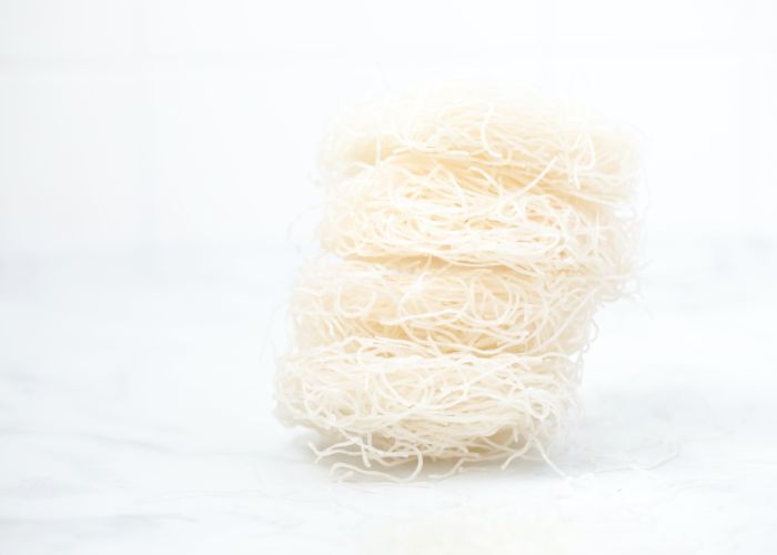 A stack of four nests of thin rice noodles against a white background