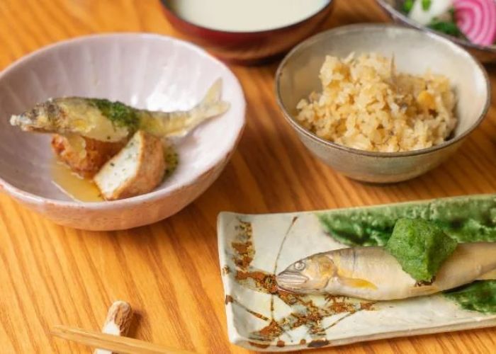 Several dishes of fish on a table, with chopsticks in the foreground