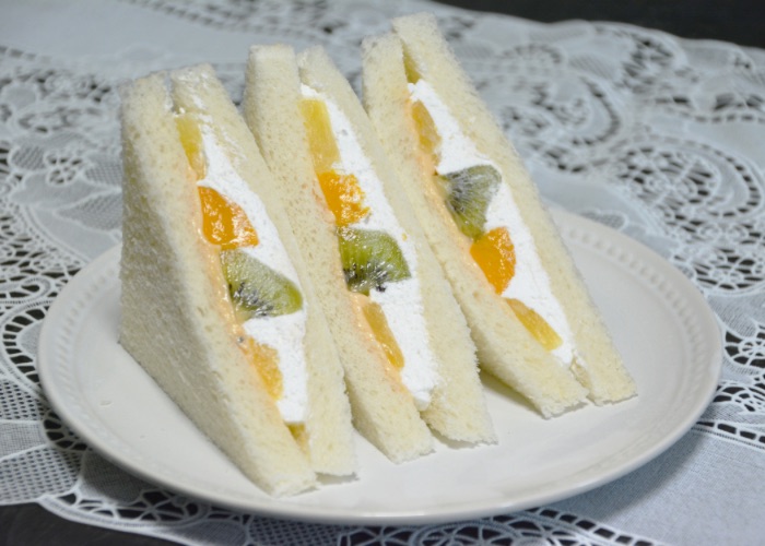 Three fruit sandwiches on a plate.