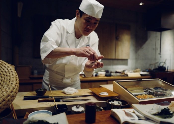 Japanese chef in white uniform preparing a meal