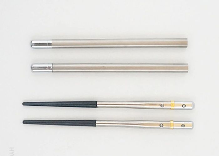 An overhead image of a pair of silver-and-black pocket chopsticks and their case