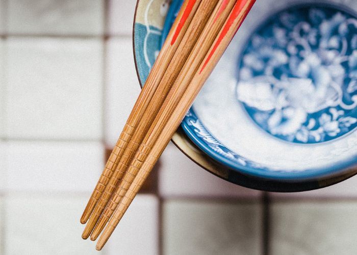 Four wooden chopsticks resting on top of a stack of bowls