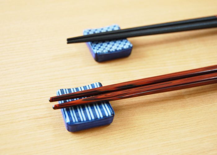 Two pairs of chopsticks with the tips resting on blue and white ceramic chopstick rests