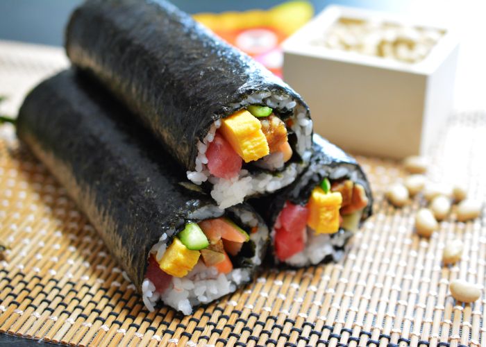 Three rolls of sushi stacked in a pyramid on a bamboo rolling mat