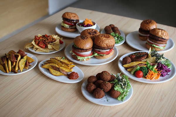 Assorted gourmet burgers and sides on a wooden table