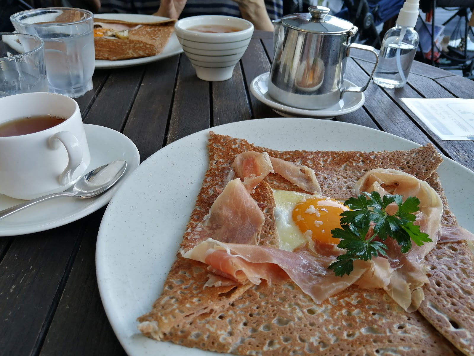 Rustic breakfast crepe with prosciutto and egg garnish at a cozy cafe