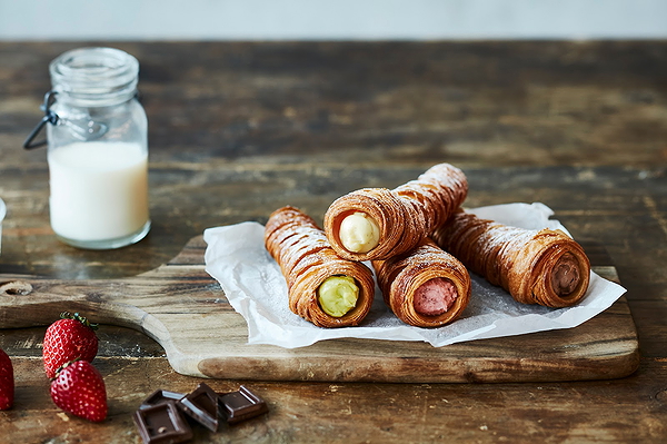 Assorted filled pastries on wooden board with milk