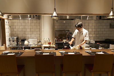 Chef prepares meal in modern open kitchen at stylish restaurant
