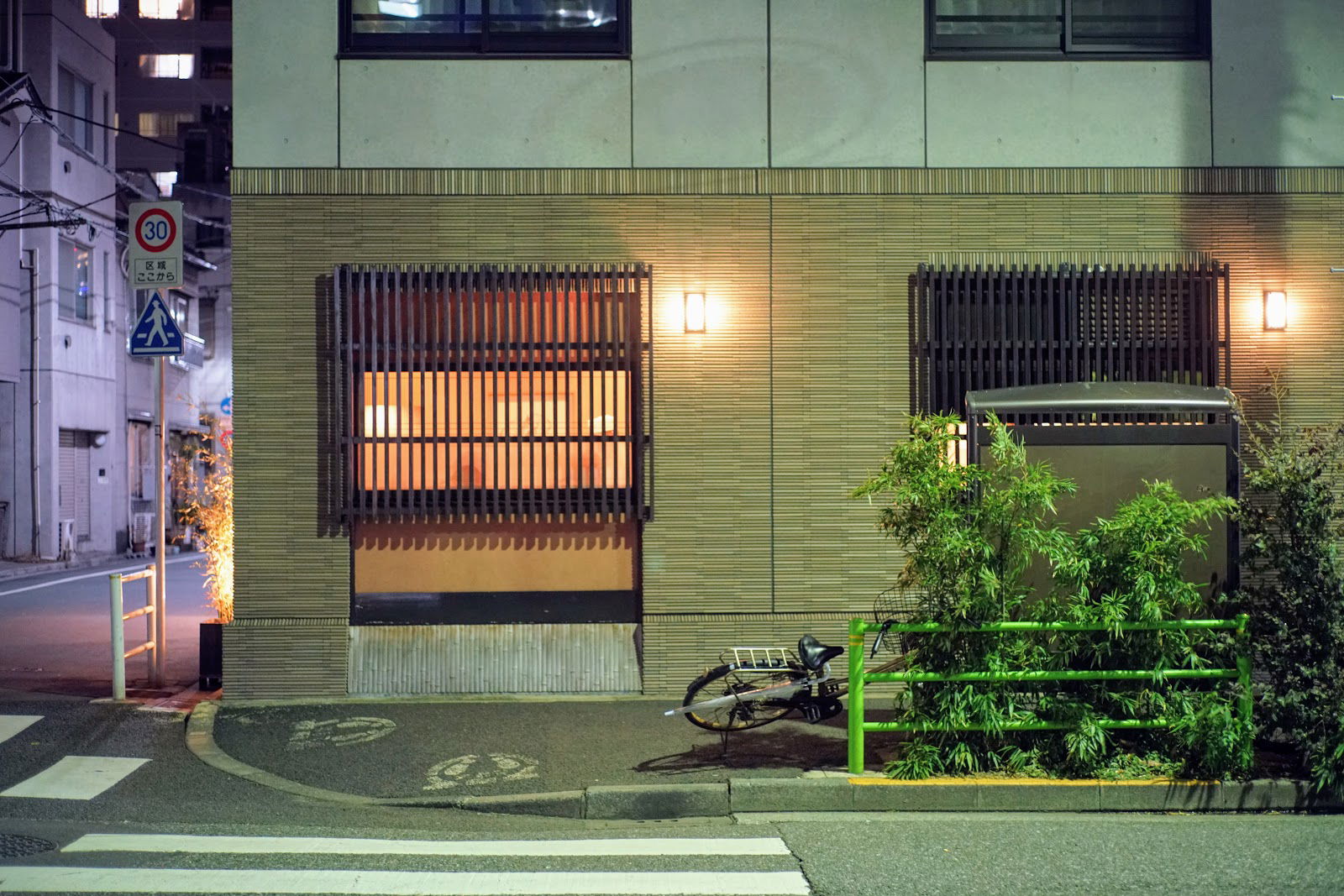 Cozy urban restaurant facade at night with bamboo plants