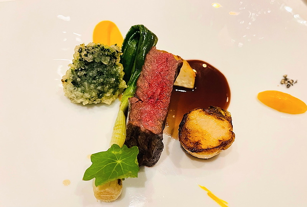 Gourmet beef dish with vegetables and sauce on a white plate
