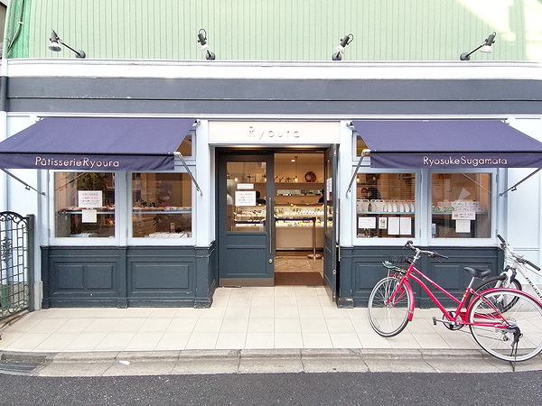 Charming pastry shop entrance with blue awnings and a red bicycle