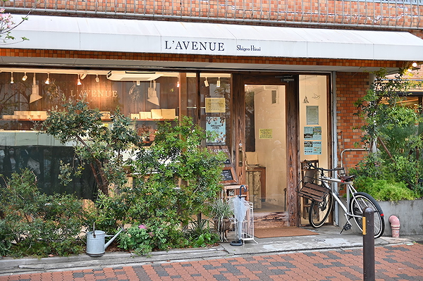 Charming outdoor facade of L'Avenue bakery with bicycle and greenery