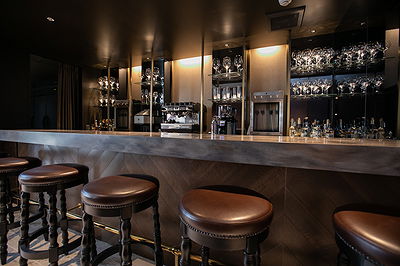 Elegant restaurant bar with leather stools and glassware display