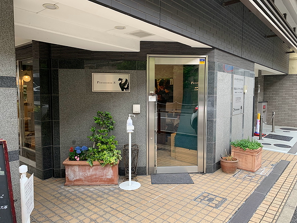 Chic restaurant entrance with modern glass door and potted plants