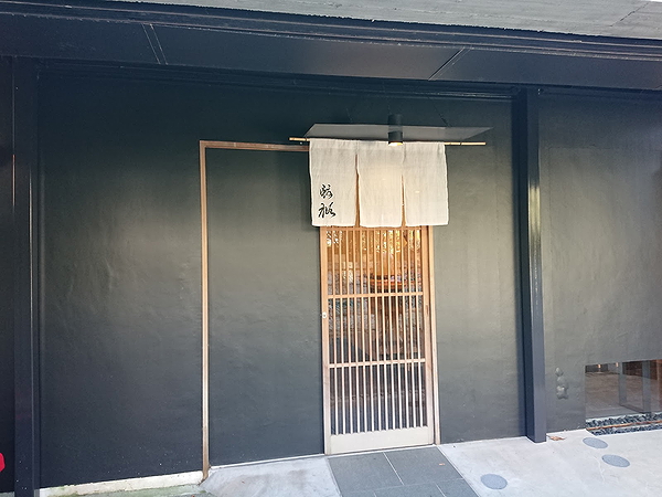 Contemporary restaurant entrance with sleek black facade and wooden door