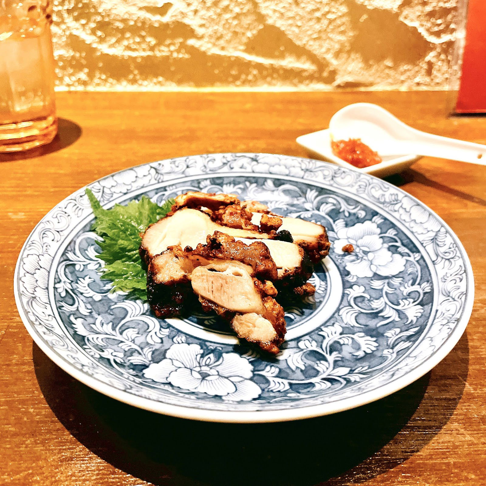 Grilled chicken on a blue floral plate with relish, wooden table setting