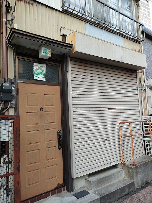 Closed restaurant exterior with metal shutter and wooden door