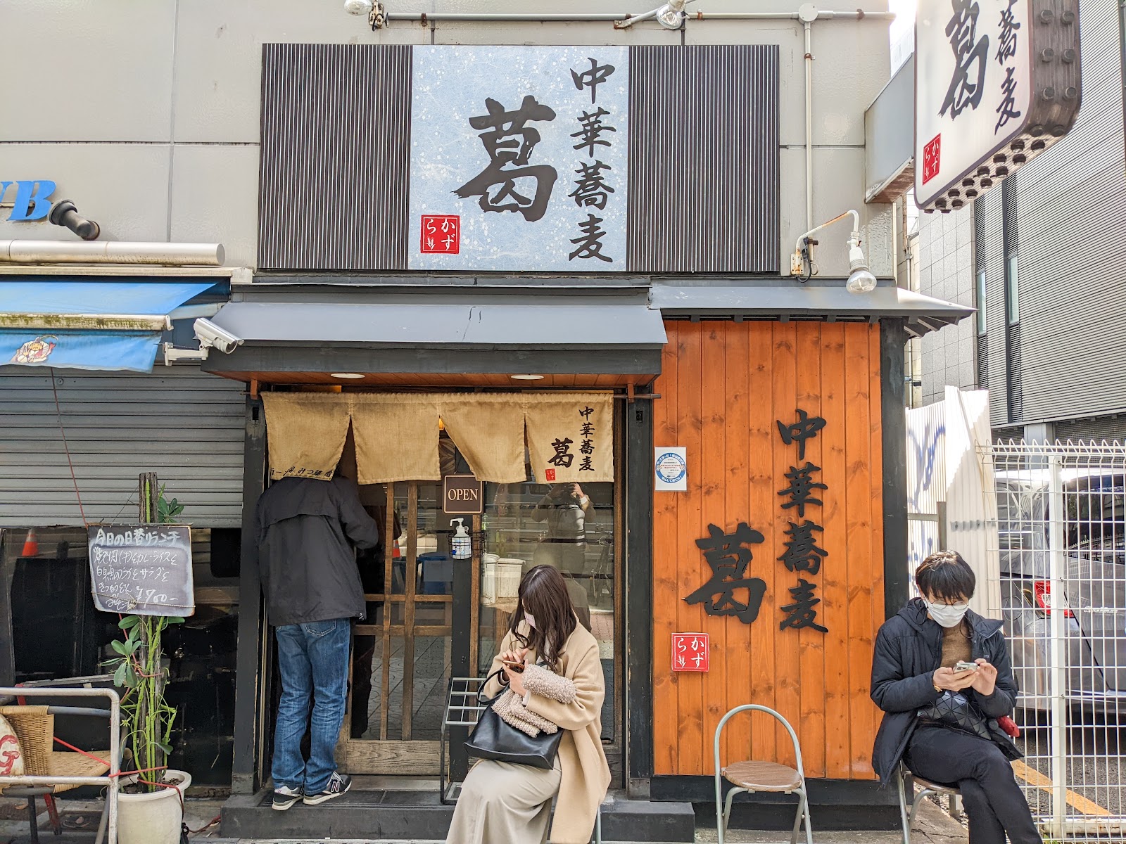 Cozy Japanese ramen shop exterior with customers seated outside.