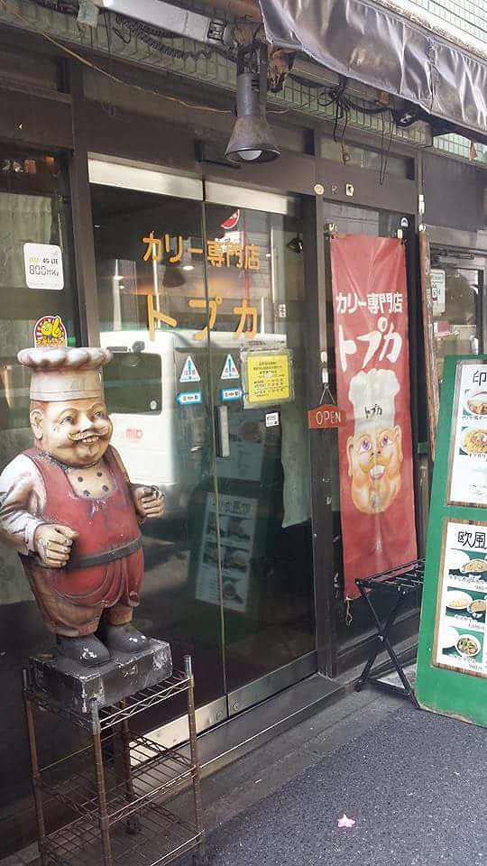 Japanese restaurant exterior with chef statue and banners