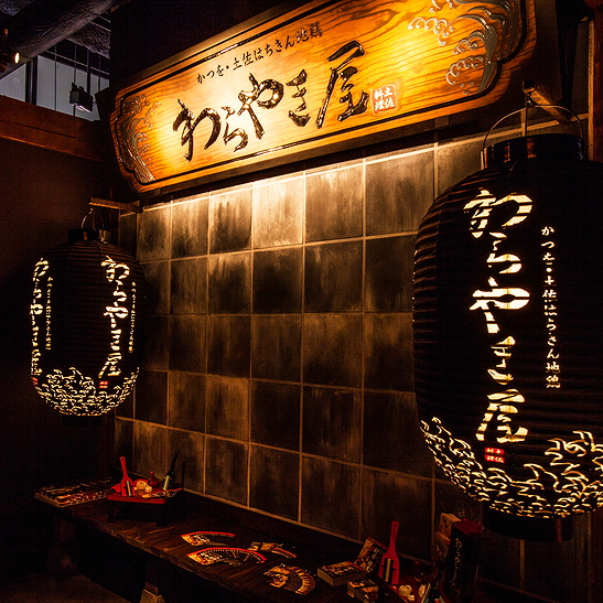 Dimly lit Japanese restaurant with decorative lanterns and wooden sign
