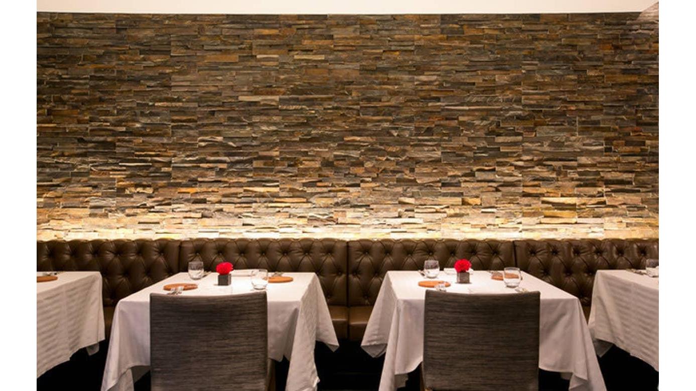 Elegant restaurant interior with stone wall and red flower centerpieces