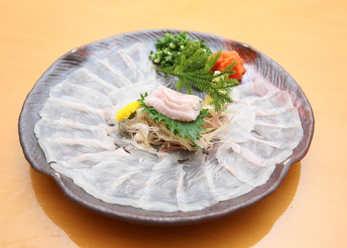 a plate of thinly sliced raw fugu fish 