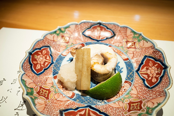 Elegantly plated fish dish with lime on decorative ceramic plate