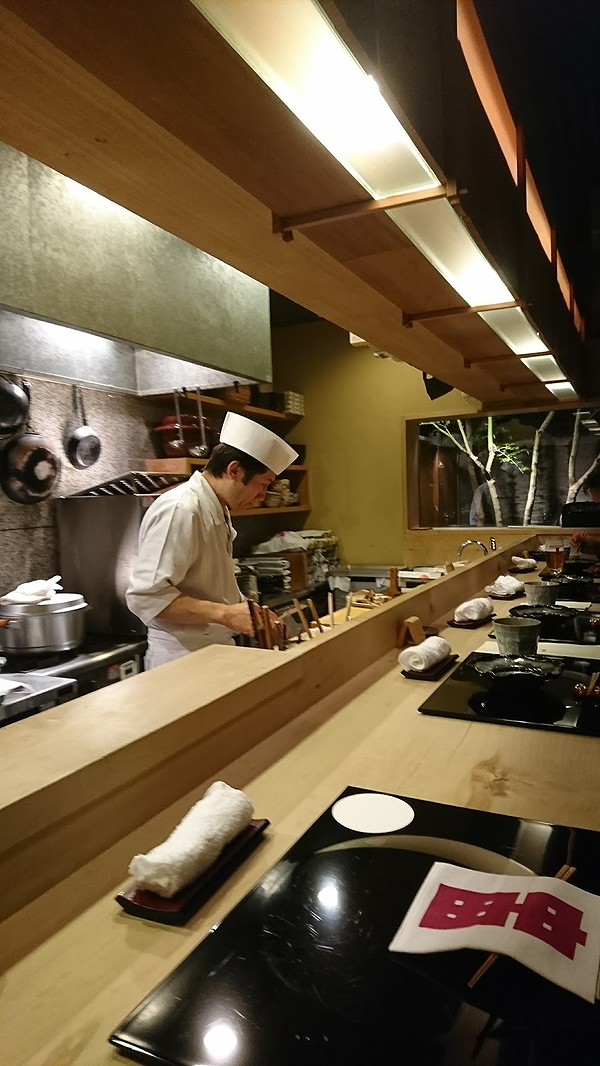 Chef preparing dishes at a modern sushi restaurant counter