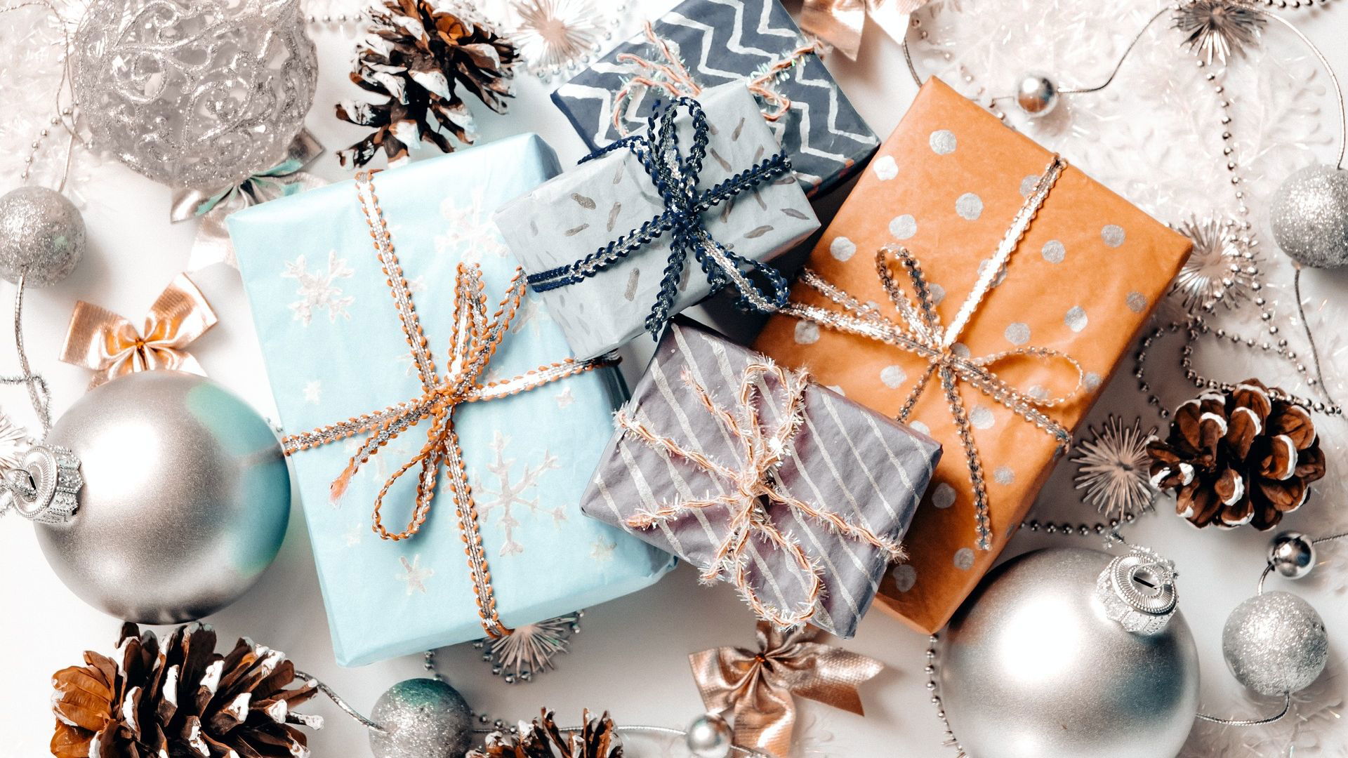 Holiday gift boxes with silver ornaments and pinecones on white