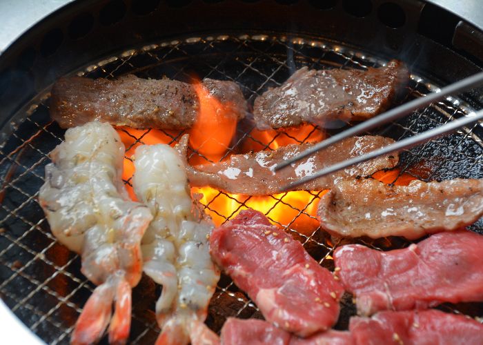 A variety of meat being cooked on a grill
