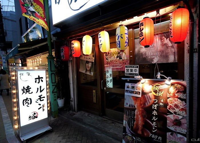 The outside of a yakiniku restaurant with many signs in Japanese 