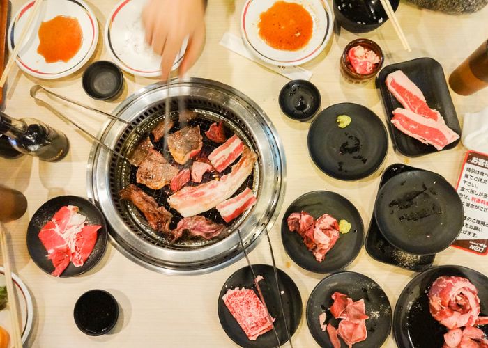 A spread of raw meat, and meat cooking on a grill at a yakiniku restaurant 