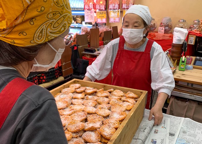 women prepare a box of senbei rice crackers