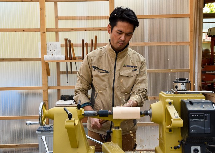 A man making a sake cup on a wood working machine 