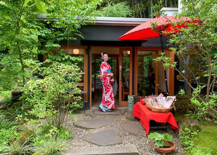 A women in knimono standing outside of a Japanese tea house