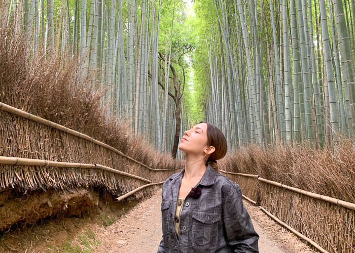 A woman standing in the Arashiyama bamboo forest in Kyoto
