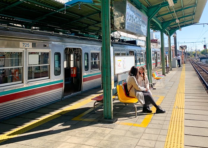 Two women wait for a train on a train platform in Japan