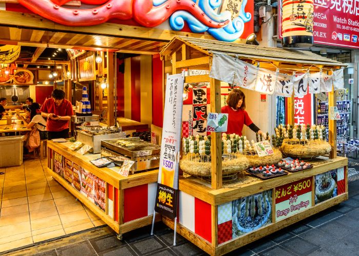 Street food stalls at Kuromon Market selling dango dumplings and other snacks