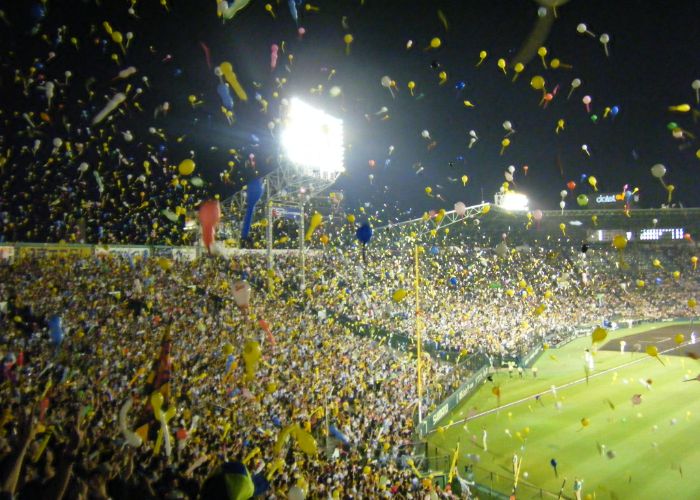 A photo taken in the stands of Koshien Stadium, with all the fans releasing balloons into the air over the baseball field