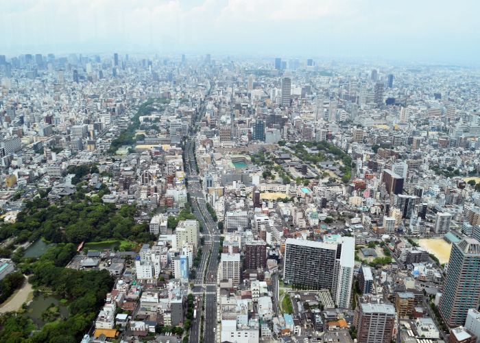 The view from the top of the Abeno Harukas building during the day, with a park, main road and lots of buildings in all directions